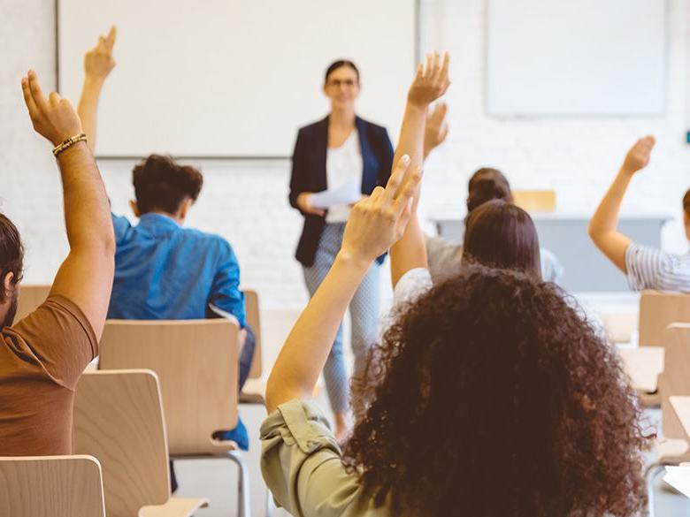 Students raising hands in classroom